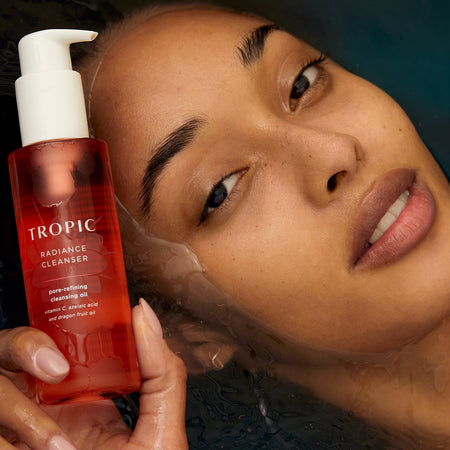 This image features a person holding a bottle of Radiance Cleanser, a pore-refining cleansing oil. The product is highlighted as being rich in Vitamin C, azelaic acid, and dragon fruit oil. The individual’s glowing, smooth complexion emphasises the cleanser’s ability to deeply cleanse and refine pores, leaving the skin radiant and refreshed.